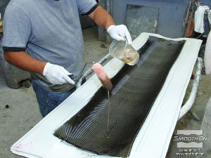 לחיצה להגדלת תמונה שופכים את האפוקסי להספגה הEpoxAmite על משטח בדי הפחם. יש להשתמש במספיק חומר כדי להרטיב ולהספיג כראוי את כל הבד.