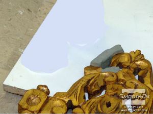 לחיצה להגדלת תמונה שמים לוח בסיס מתחת לגילוף העץ ולוחצים עליו את החימר כך שיכיל את יציקת הפוליאוריתן Smooth-Cast® 385.