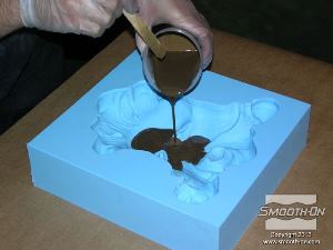 לחיצה להגדלת תמונה שופכים את התערובת אל מרכז חלל התבנית. מוודאים שלא נותרה אבקת הברונזה בכלי. עבור יציקות מסוג זה, גומי סיליקון הוא אידיאלי. במקרה זה, התבנית עשויה מסיליקון Mold Max® XLS .