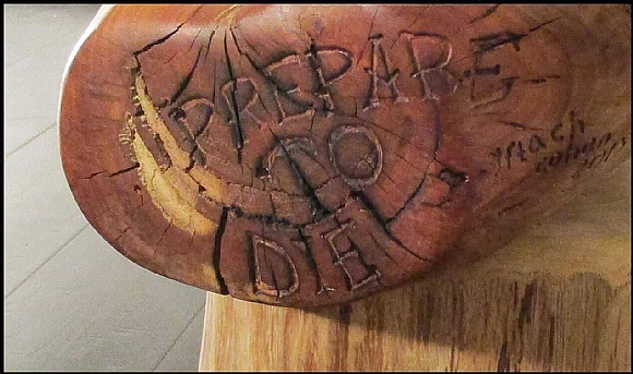 לחיצה להגדלת תמונה בסיס השולחן – כף יד ימין בעלת שש אצבעות עם הכיתוב “prepare to die”. השולחן עשוי אקליפטוס אדום על בסיס עץ מכנף נאה ומשטח זכוכית. העצים מחוברים באמצעות מוטות ברזל ודבק אפוקסי.