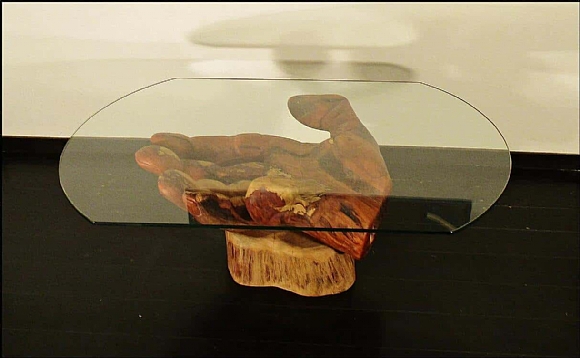 לחיצה להגדלת תמונה בסיס השולחן – כף יד ימין בעלת שש אצבעות עם הכיתוב “prepare to die”. השולחן עשוי אקליפטוס אדום על בסיס עץ מכנף נאה ומשטח זכוכית. העצים מחוברים באמצעות מוטות ברזל ודבק אפוקסי.