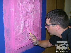 לחיצה להגדלת תמונה בוחנים את המודל מכל הזווית (אפילו מלמטה) כדי להיות בטוחים שהוא מכוסה לגמרי בסיליקון Mold Max® Stroke. מורחים חומר גם על משטח העבודה מסביב למודל כדי ליצור מעין מסגרת שתעזור בנעילת התבנית במעיל התמיכה בהמשך (מסגרת זו נקראת גם פלאנג' Flange).