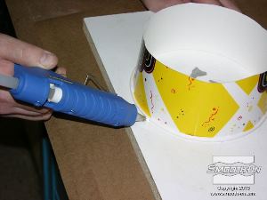 לחיצה להגדלת תמונה ממקמים את מיכל הנייר על לוח המלאמין, מסביב לצלקות. מדביקים את המיכל בעזרת דבק חם ללוח.