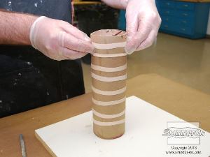 לחיצה להגדלת תמונה שמים מחדש את גומיות הדואר על גליל הקרטון כדי לאבטח את התבנית בזמן היציקה.