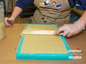 לחיצה להגדלת תמונה דוחפים את הפוליאורתן למריחה Plasti-Paste® II אל תוך פרטי תבנית הסיליקון ומפלסים אותו.