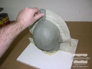 לחיצה להגדלת תמונה מפסלים מ חימר לעיצוב חתיכה שתהווה תעלה ליציקת החומר לתבנית בהמשך ומניחים אותה על משטח הפסל המקורי.