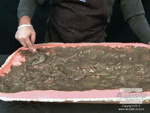 לחיצה להגדלת תמונה מפזרים את החומר בתבנית בעזרת מברשת בזמן שהחומר מתחיל להתפשט.