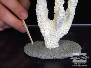 לחיצה להגדלת תמונה יוצרים בחימר מרקם מציאותי בעזרת מקל ארטיק שבור. המטרה היא לחקות אפקט של מבנה אלמוג אמיתי.