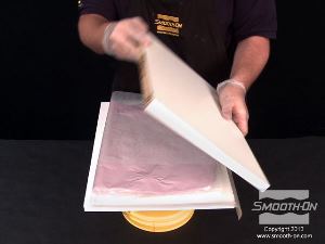 לחיצה להגדלת תמונה משאירים את התבנית עם המודל המקורי על חצי לוח אחד ומגביהים את הלוח ותבנית הסיליקון Equinox® 40 מספיק כדי שיהיה אפשר לתפוס את פינות הלוח במלחציים בהמשך.