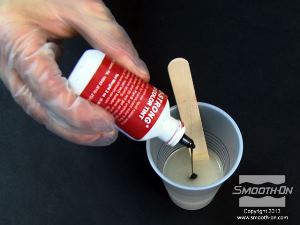 לחיצה להגדלת תמונה מעבירים את המקשה של הפוליאוריטן ליציקה Smooth-Cast® 60D למיכל ערבוב גדול יותר ומוסיפים לו מספר טיפות של פיגמנט SO-Strong אדום.