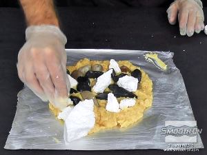 לחיצה להגדלת תמונה שוברים את הקלקר לחתיכות קטנות באופן אקראי. מטביעים את חתיכות הקלקר בתערובת הפוליאוריטן/פילר בין חלוקי הנחל וסביב הקצוות החיצוניים.