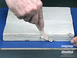 לחיצה להגדלת תמונה מיישרים את קצוות מיטת החימר כך שתתאים בדיוק למסגרת התבנית.