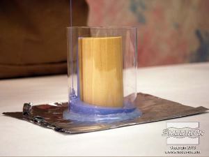 לחיצה להגדלת תמונה שמים את מעטפת האקריליק מסביב לגליל העץ. יוצקים את הסיליקון OOMOO® 30 הנוזלי אל תחתית המיכל בזרם ארוך ודק ומניחים לו לעלות על מודל העץ, כדי למנוע לכידה של בועות אוויר.