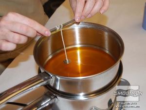 לחיצה להגדלת תמונה כדי לאבטח את בסיס הפתיל לתחתית התבנית, טובלים אותו בשעווה החמה.